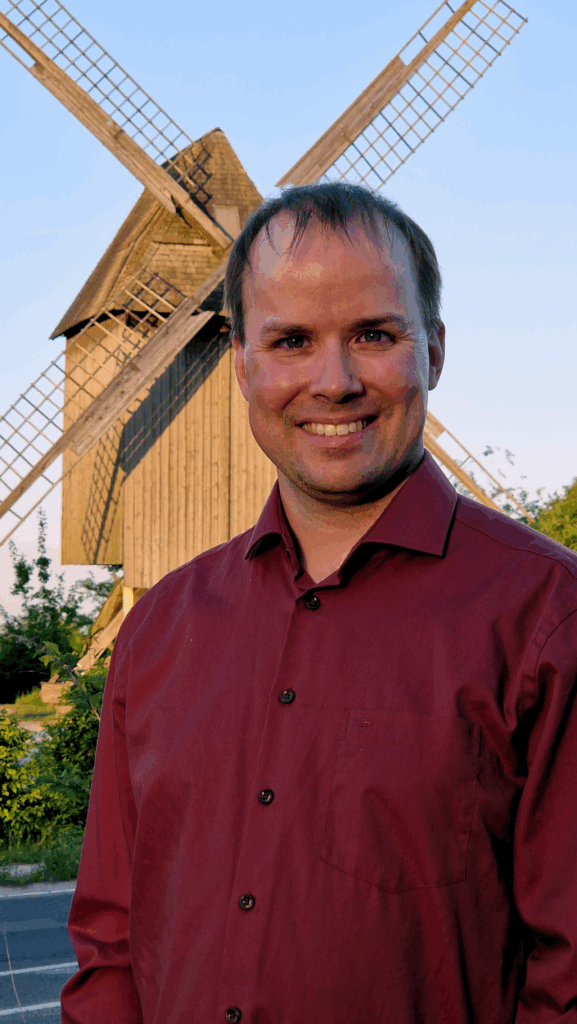 Helge Steinecke vor der Sorgenser Mühle, freundlich lächelnd, in rostrotem Hemd.