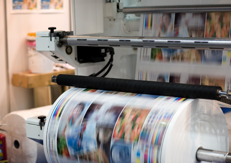 Druckmaschine im Einsatz mit laufendem, farbigen Papierdruck.